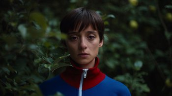 Movie still from “Copenhagen Cowboy” (2022), created by Nicolas Winding Refn – A woman with short hair wearing a blue and red jacket; Close Up shot, Low angle