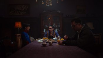 Movie still from “Copenhagen Cowboy” (2022), created by Nicolas Winding Refn – Three people sitting at a dinner table with food; Medium shot, Low angle