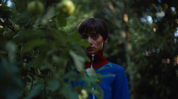 Movie still from “Copenhagen Cowboy” (2022), created by Nicolas Winding Refn – A woman standing in the middle of an apple orchard; Close Up shot, High angle