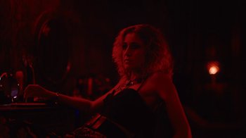 Movie still from “Copenhagen Cowboy” (2022), created by Nicolas Winding Refn – A woman in a black dress is playing a guitar; Medium shot, Low angle
