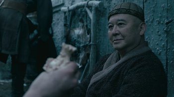 Movie still from “Vikings” (2013), created by Michael Hirst – An older man holding a piece of pizza in his hand; Close Up shot, Over the shoulder angle