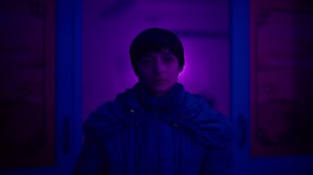 Movie still from “Copenhagen Cowboy” (2022), created by Nicolas Winding Refn – A person standing in front of a purple light; Medium shot, Low angle