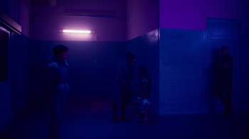 Movie still from “Copenhagen Cowboy” (2022), created by Nicolas Winding Refn – A couple of people standing next to each other in a dark room; Wide shot, Over the shoulder angle