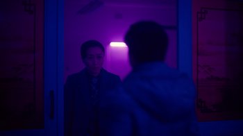 Movie still from “Copenhagen Cowboy” (2022), created by Nicolas Winding Refn – A woman standing in front of a mirror in a room; Medium shot, Over the shoulder angle