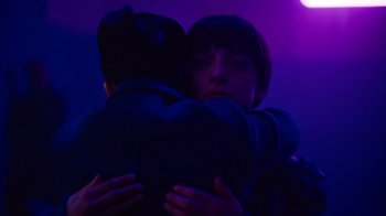 Movie still from “Copenhagen Cowboy” (2022), created by Nicolas Winding Refn – Two people hugging in a dark room with purple lighting; Close Up shot, Low angle