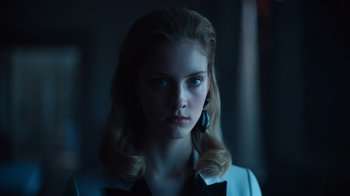 Movie still from “Copenhagen Cowboy” (2022), created by Nicolas Winding Refn – A young woman with long blonde hair wearing a white jacket; Close Up shot, Low angle