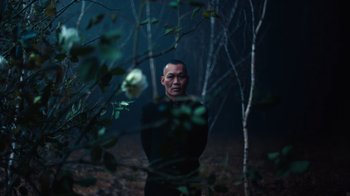 Movie still from “Copenhagen Cowboy” (2022), created by Nicolas Winding Refn – A man standing in the middle of a forest; Medium shot, Low angle
