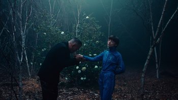 Movie still from “Copenhagen Cowboy” (2022), created by Nicolas Winding Refn – A man and a boy are in the woods; Medium shot, Low angle
