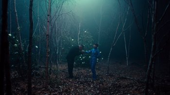 Movie still from “Copenhagen Cowboy” (2022), created by Nicolas Winding Refn – Two people in the woods touching each other's hands; Wide shot, Over the shoulder angle