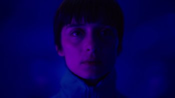 Movie still from “Copenhagen Cowboy” (2022), created by Nicolas Winding Refn – A young man is glowing in the blue light; Close Up shot, Low angle
