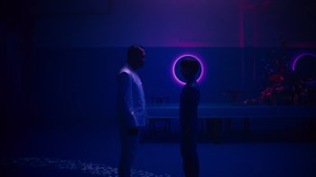 Movie still from “Copenhagen Cowboy” (2022), created by Nicolas Winding Refn – Two people standing in a room with a purple light in the background; Wide shot, Low angle