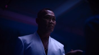 Movie still from “Copenhagen Cowboy” (2022), created by Nicolas Winding Refn – A man in a white robe standing in a dark room; Close Up shot, Low angle