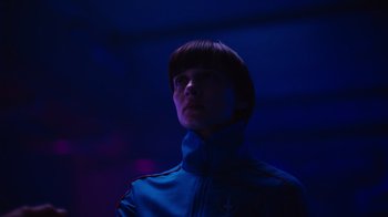 Movie still from “Copenhagen Cowboy” (2022), created by Nicolas Winding Refn – A man in a blue jacket standing in the dark; Close Up shot, Low angle