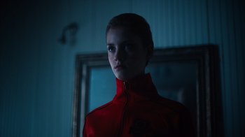 Movie still from “Copenhagen Cowboy” (2022), created by Nicolas Winding Refn – A woman wearing a red jacket standing in front of a mirror; Close Up shot, Low angle