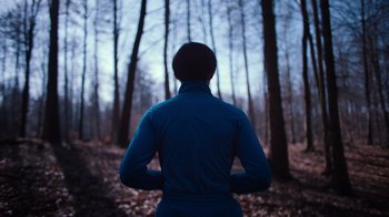 Movie still from “Copenhagen Cowboy” (2022), created by Nicolas Winding Refn – A person standing in the middle of a forest; Medium shot, Low angle