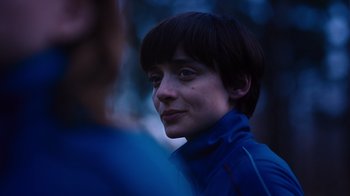 Movie still from “Copenhagen Cowboy” (2022), created by Nicolas Winding Refn – A young person in a blue jacket looking at the camera; Close Up shot, Over the shoulder angle