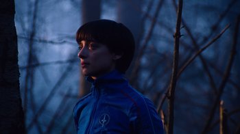 Movie still from “Copenhagen Cowboy” (2022), created by Nicolas Winding Refn – A person standing in the woods at night; Close Up shot, Low angle