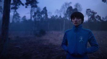 Movie still from “Copenhagen Cowboy” (2022), created by Nicolas Winding Refn – A person standing in the middle of a field; Medium shot, Over the shoulder angle