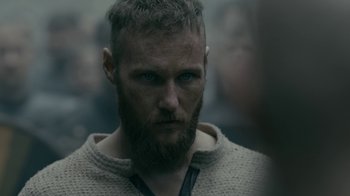 Movie still from “Vikings” (2013), created by Michael Hirst – A person with a beard wearing a sweater; Close Up shot, Over the shoulder angle