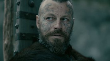 Movie still from “Vikings” (2013), created by Michael Hirst – A person with a beard and tattoos; Close Up shot, Low angle