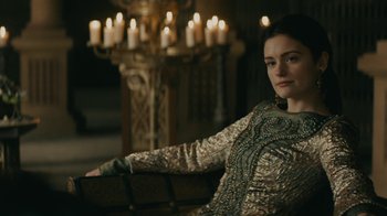 Movie still from “Vikings” (2013), created by Michael Hirst – A woman sitting on a bench in front of candles; Medium shot, Over the shoulder angle