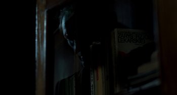 Movie still from “Cracow Monsters” (2022), created by Kasia Adamik – A person with a book in a dark room; Extreme Close Up shot, Over the shoulder angle