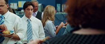 Movie still from “Wanted” (2008), directed by Timur Bekmambetov – A group of people standing around each other in a room; Medium shot, Over the shoulder angle