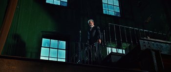 Movie still from “Wanted” (2008), directed by Timur Bekmambetov – An older man standing on a railing next to a window; Wide shot, Low angle