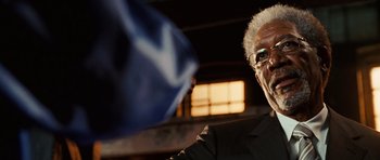 Movie still from “Wanted” (2008), directed by Timur Bekmambetov – An older man in a black suit and glasses; Close Up shot, Over the shoulder angle