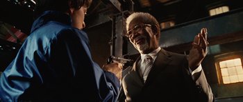 Movie still from “Wanted” (2008), directed by Timur Bekmambetov – An older man in a suit and tie holding a gun; Close Up shot, Over the shoulder angle