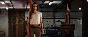 Movie still from “Wanted” (2008), directed by Timur Bekmambetov – A woman holding a gun while standing in a room; Medium shot, Low angle