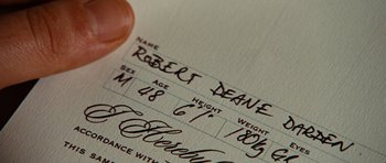 Movie still from “Wanted” (2008), directed by Timur Bekmambetov – A person's hand writing on a receipt; Extreme Close Up shot, Overhead angle
