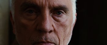 Movie still from “Wanted” (2008), directed by Timur Bekmambetov – An older man with a gray beard and blue eyes; Extreme Close Up shot, Low angle