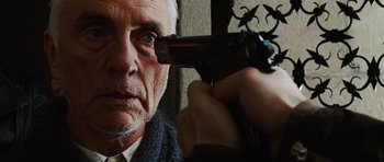 Movie still from “Wanted” (2008), directed by Timur Bekmambetov – An older man holding a gun up to his face; Close Up shot, Over the shoulder angle