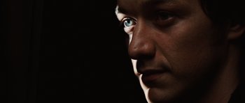 Movie still from “Wanted” (2008), directed by Timur Bekmambetov – A person's face with a black background; Extreme Close Up shot, High angle