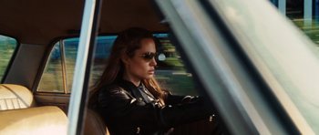 Movie still from “Wanted” (2008), directed by Timur Bekmambetov – A woman driving a car wearing a leather jacket and sunglasses; Medium shot, Over the shoulder angle