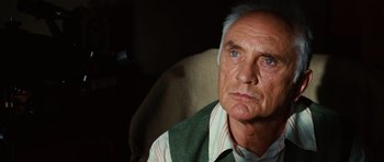 Movie still from “Wanted” (2008), directed by Timur Bekmambetov – An older man sitting in a chair looking at the camera; Close Up shot, Low angle