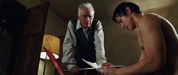 Movie still from “Wanted” (2008), directed by Timur Bekmambetov – An older man and a young woman looking at papers on a table; Medium shot, Low angle