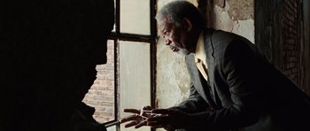 Movie still from “Wanted” (2008), directed by Timur Bekmambetov – An older man wearing a suit and tie looking out of a window; Close Up shot, Low angle