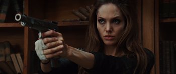 Movie still from “Wanted” (2008), directed by Timur Bekmambetov – A beautiful woman holding a gun while wearing a black shirt; Close Up shot, Over the shoulder angle