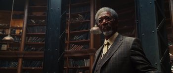 Movie still from “Wanted” (2008), directed by Timur Bekmambetov – An older man wearing a suit and tie in front of bookshelves; Close Up shot, Low angle