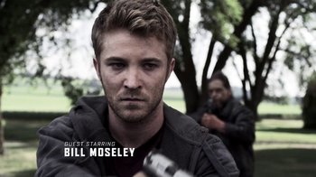 Movie still from “Z Nation” (2014), created by Karl Schaefer – A person holding a gun with trees in the background; Close Up shot, Low angle