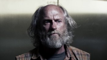 Movie still from “Z Nation” (2014), created by Karl Schaefer – An old man with a beard and a plaid shirt; Close Up shot, Low angle