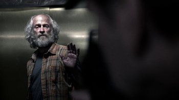 Movie still from “Z Nation” (2014), created by Karl Schaefer – An older man with a beard and a plaid shirt; Medium shot, Over the shoulder angle