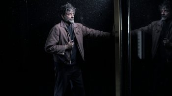 Movie still from “Z Nation” (2014), created by Karl Schaefer – A man standing in front of a glass window; Medium shot, Low angle
