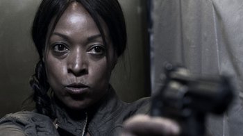 Movie still from “Z Nation” (2014), created by Karl Schaefer – A woman holding a gun in front of a mirror; Close Up shot, Over the shoulder angle