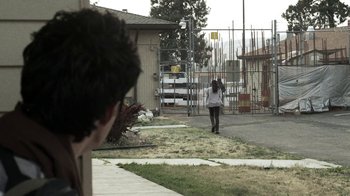 Movie still from “Z Nation” (2014), created by Karl Schaefer – A person walking in front of a building; Extreme Wide shot, Over the shoulder angle