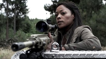 Movie still from “Z Nation” (2014), created by Karl Schaefer – A woman is holding a rifle and looking through the scope; Close Up shot, Over the shoulder angle