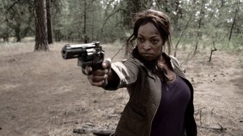 Movie still from “Z Nation” (2014), created by Karl Schaefer – A woman holding a gun in a field; Close Up shot, Over the shoulder angle