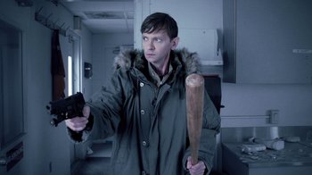 Movie still from “Z Nation” (2014), created by Karl Schaefer – A man holding a baseball bat and a remote control; Medium shot, Over the shoulder angle
